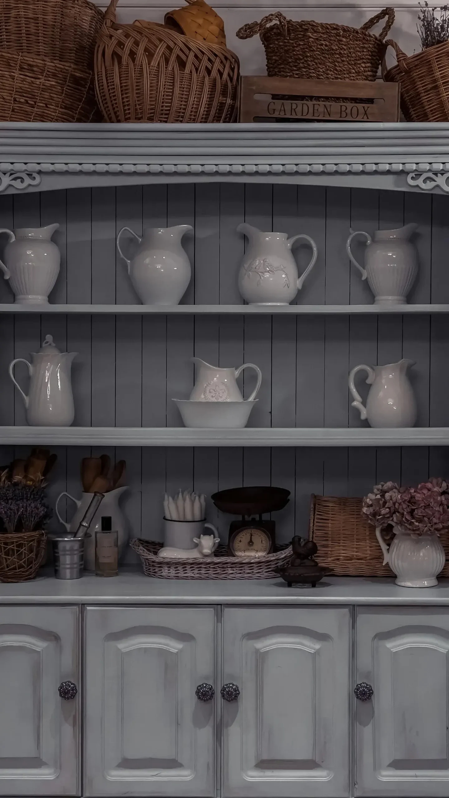 Bright kitchen interior with a white wooden sideboard cupboard and ceramic tableware on shelves