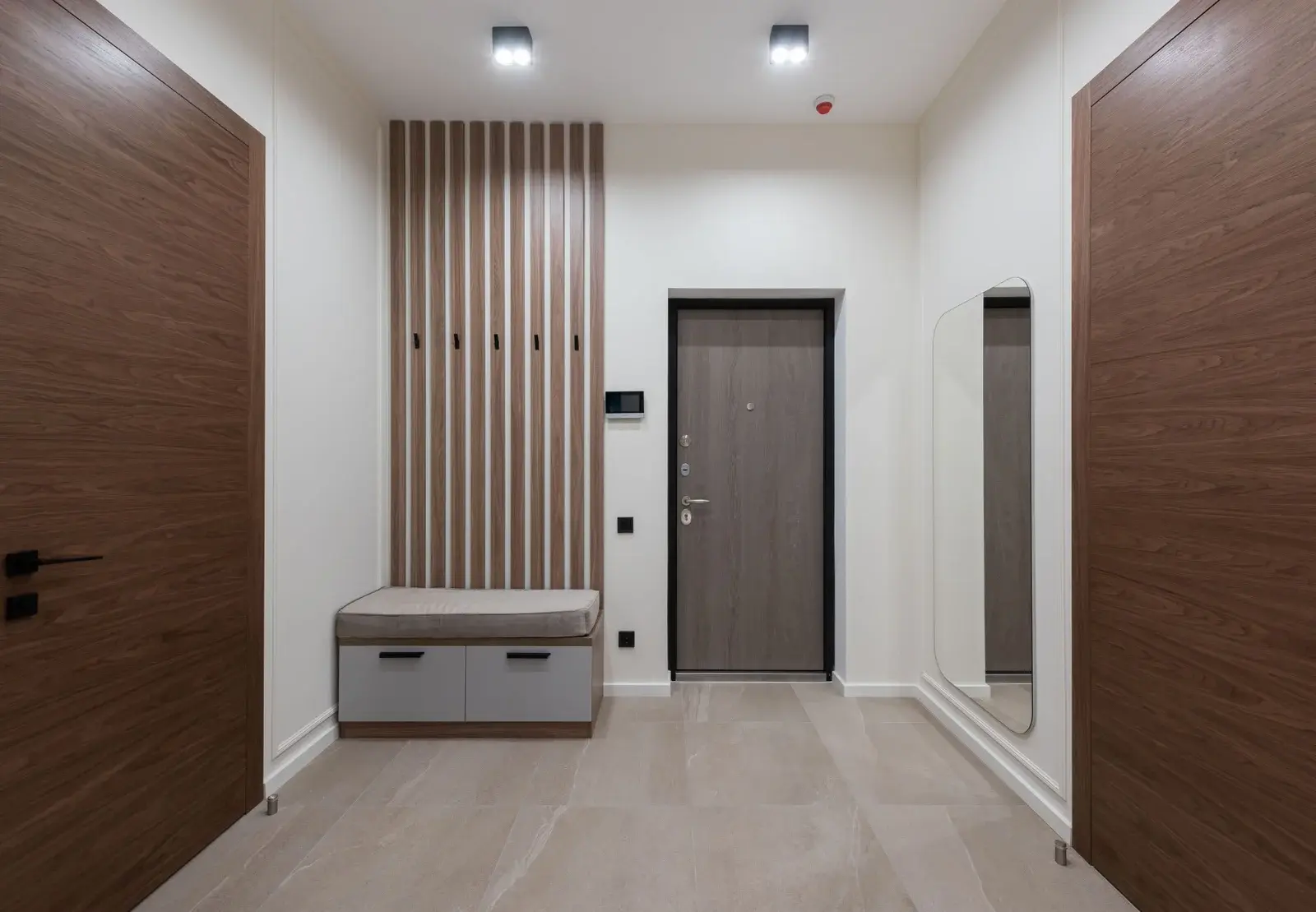 Bright modern hallway with floor-to-ceiling built-in wardrobe, wooden accents, and a large backlit illuminated mirror.