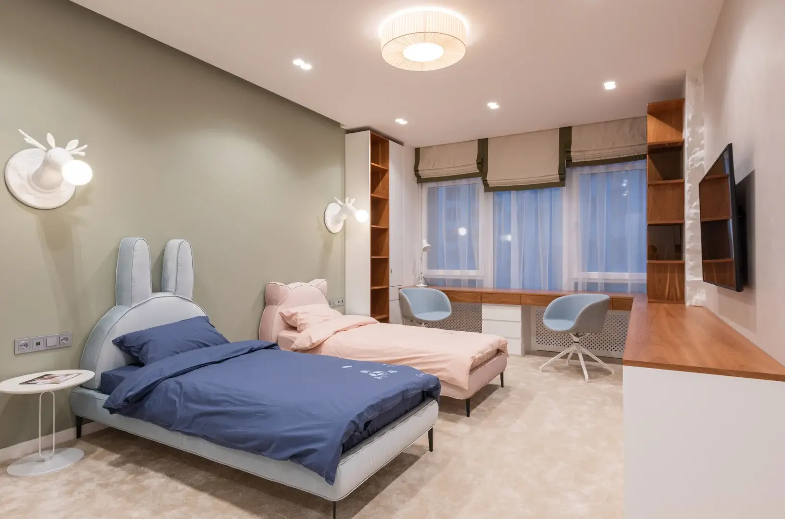Jasny pokój dziecięcy z pomalowaną na szałwiowy kolor ścianą i drewnianymi meblami