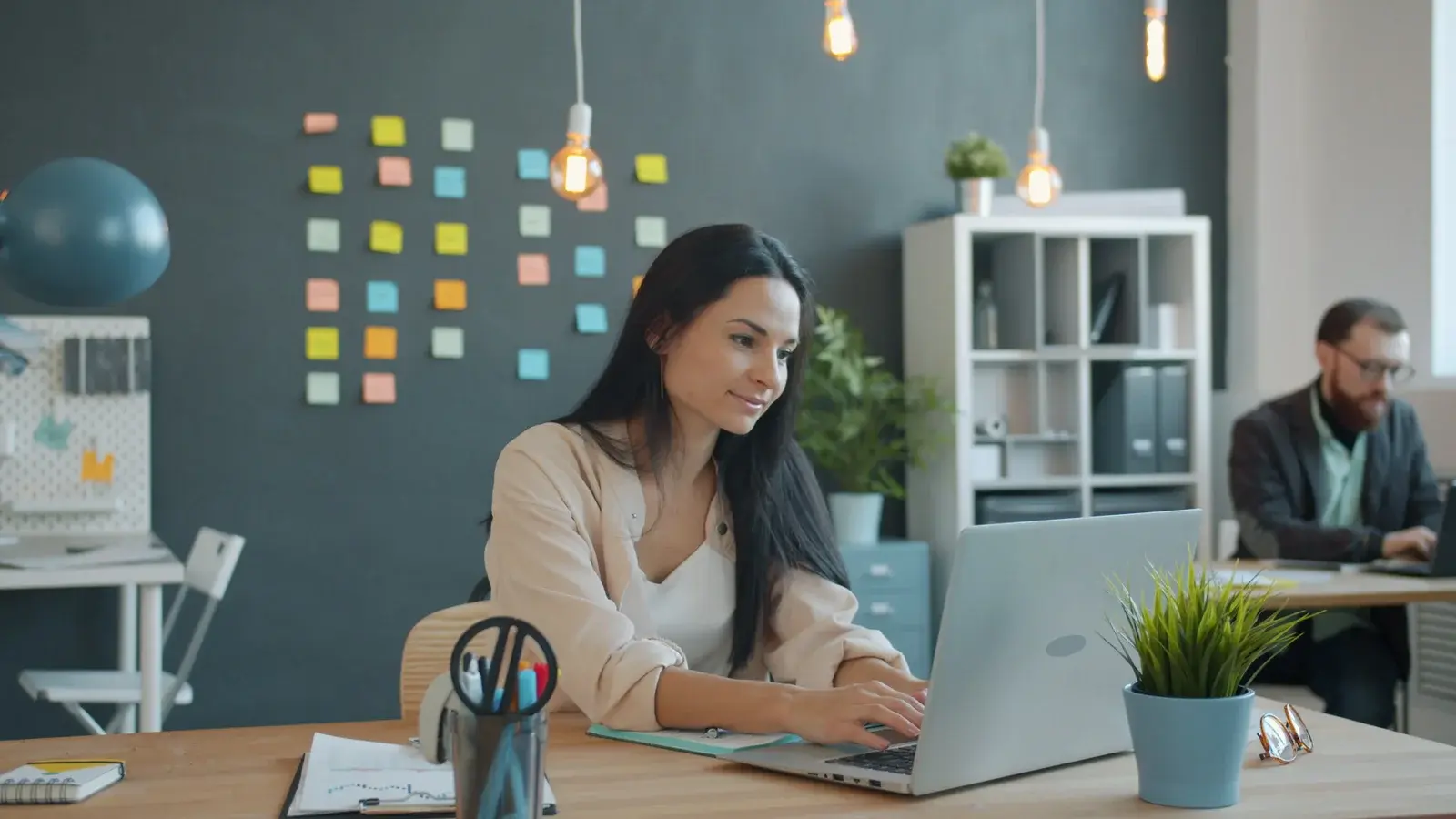 Nowoczesne biuro otwarte z ergonomicznymi biurkami, zieloną ścianą i strefą chillout