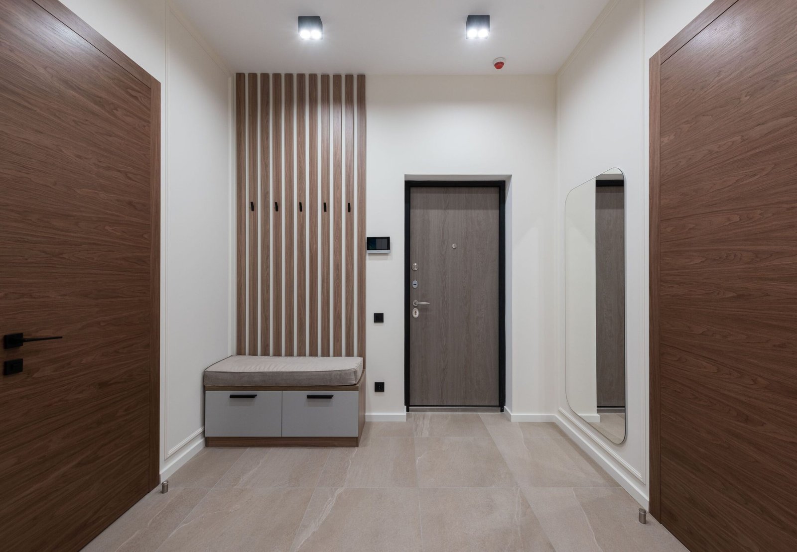 Bright modern hallway with floor-to-ceiling built-in wardrobe, wooden accents, and a large backlit illuminated mirror.