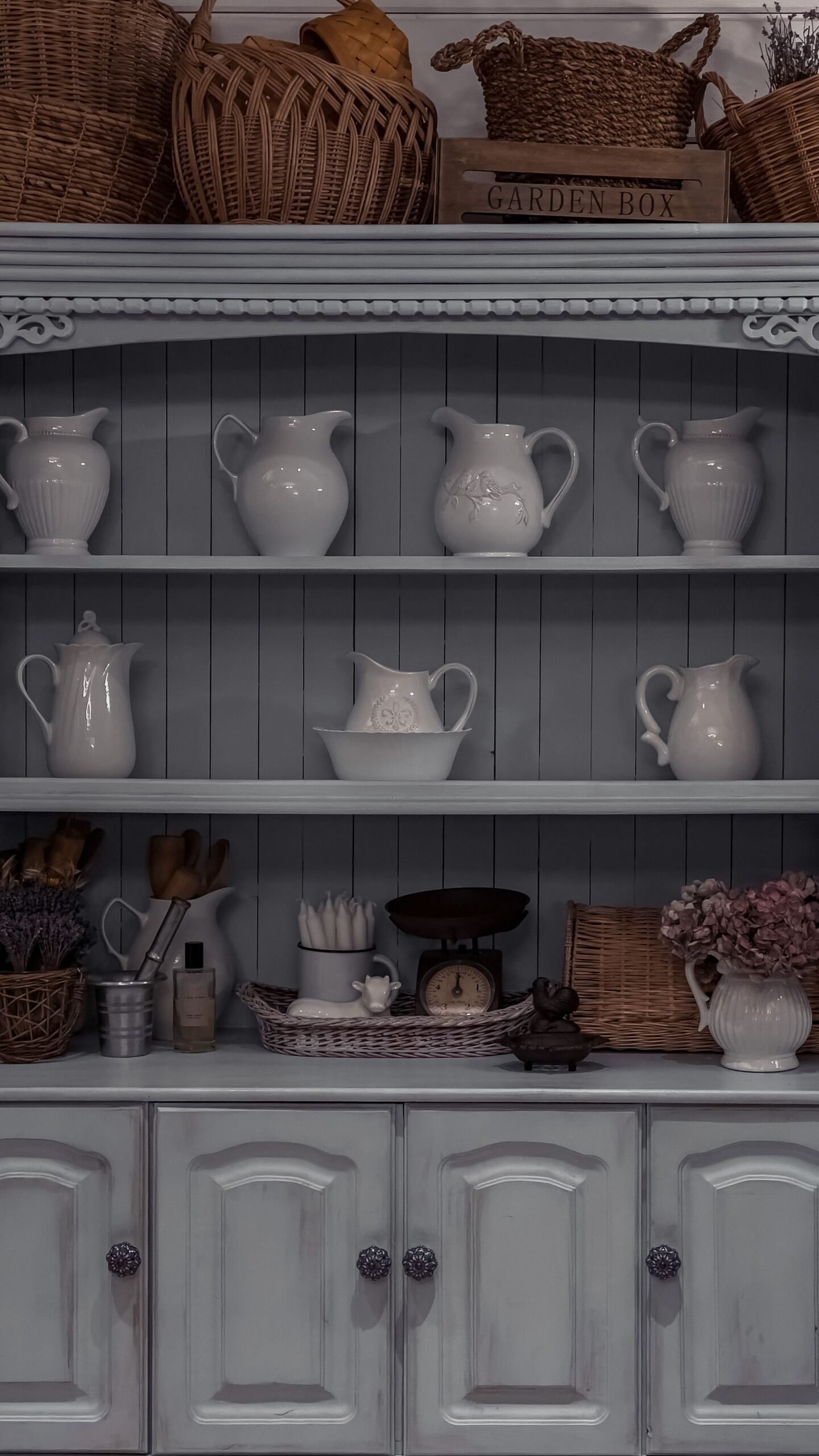 Bright kitchen interior with a white wooden sideboard cupboard and ceramic tableware on shelves