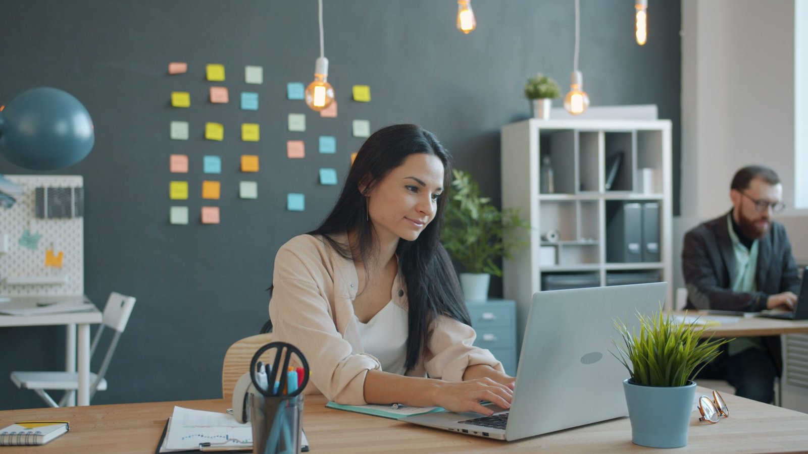 Nowoczesne biuro otwarte z ergonomicznymi biurkami, zieloną ścianą i strefą chillout